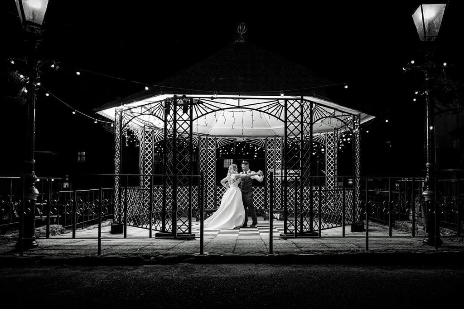 A couple dancing in the lit bandstand at night